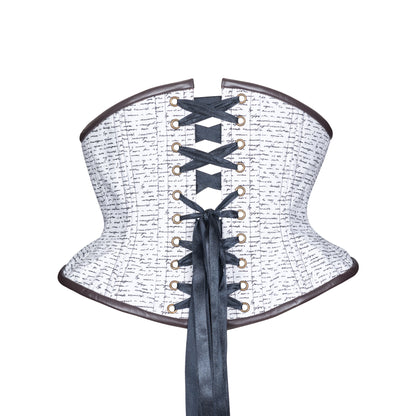 A structured corset with a white fabric body covered in black cursive script, dark brown leather binding trim along the top and bottom edges, antique brass grommets and black satin ribbon lacing down the back, shown on a plain white background.